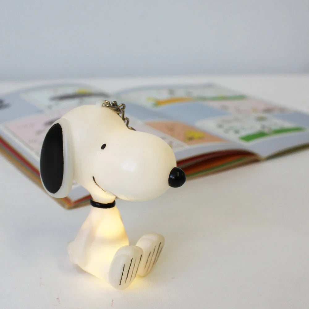 Snoopy keyring sitting on a surface with its light glowing.