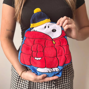 	Woman holding Peanuts Snoopy Puffa Hot Water Bottle with red puffa coat design.