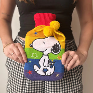 Person holding Snoopy Rainbow Hot Water Bottle with colourful knit cover and pompoms.