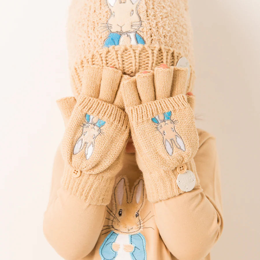 Child wearing matching Peter Rabbit™ hat and mittens in neutral tan knit, featuring embroidered Peter Rabbit design.