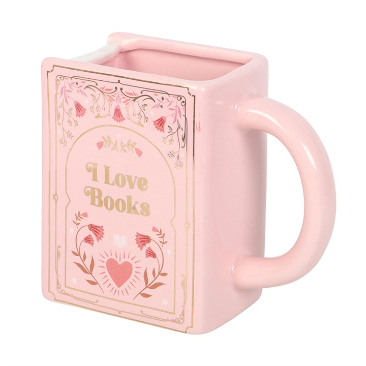 Angled view of pink ceramic mug shaped like a book with decorative floral illustration.