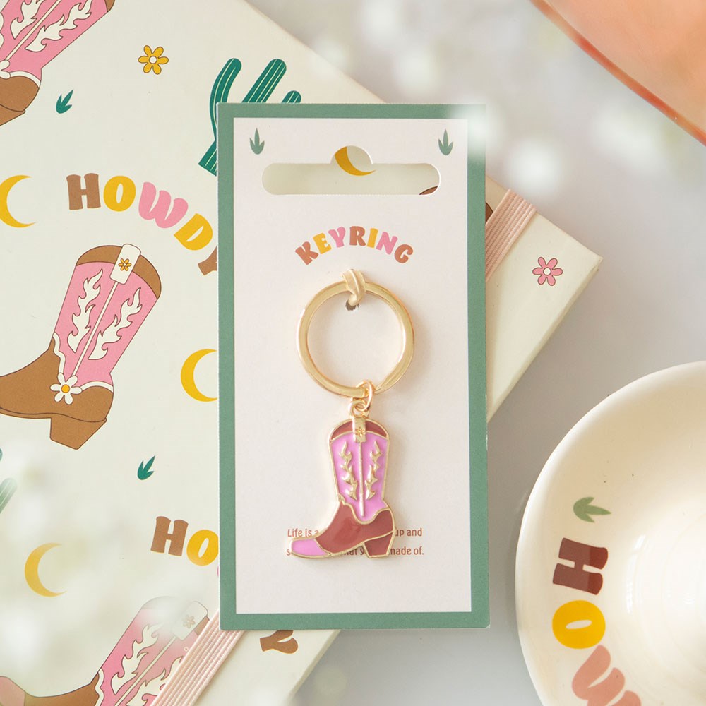 Pink cowboy boot keyring with gold details on display card.
