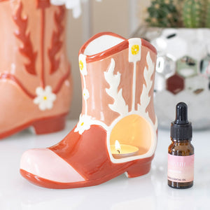 Pink cowboy boot ceramic oil burner with tea light and essential oil bottle, styled on a dressing table.