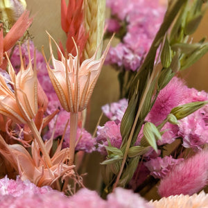 A detailed shot of the handcrafted pink dried flower bouquet, featuring wheat stems and delicate blossoms.