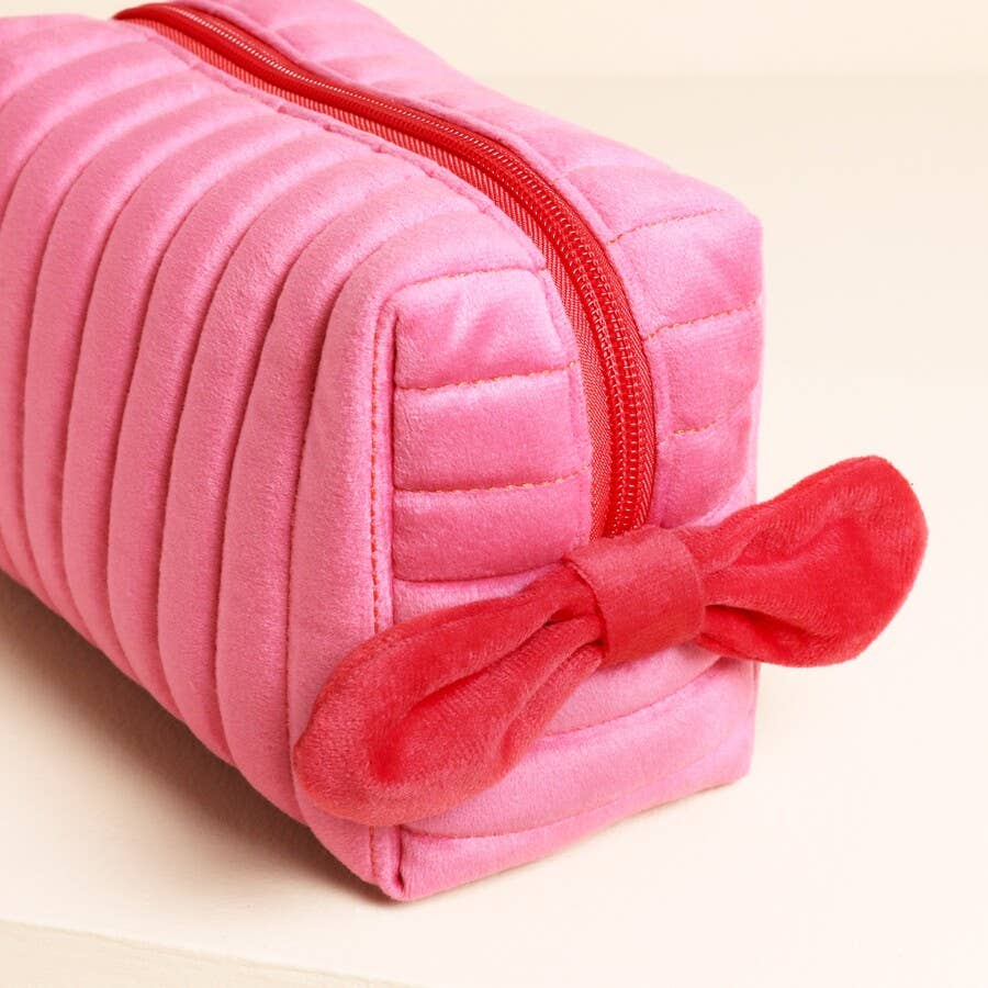 Close-up of red velvet bow detail on pink quilted washbag.