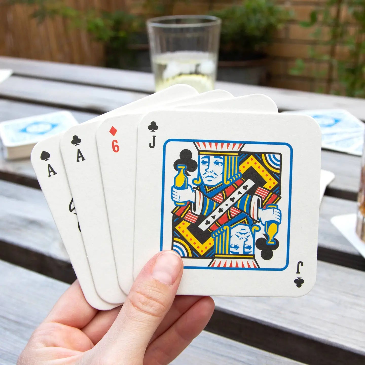 Hand holding Playing Card Drink Mats full house.
