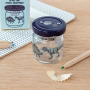 Dinosaur glass jar pencil sharpener on desk with pencils and shavings
