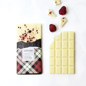 Handmade Cranachan white chocolate bar with whisky, freeze-dried raspberries, and oats, wrapped in a red tartan paper design.