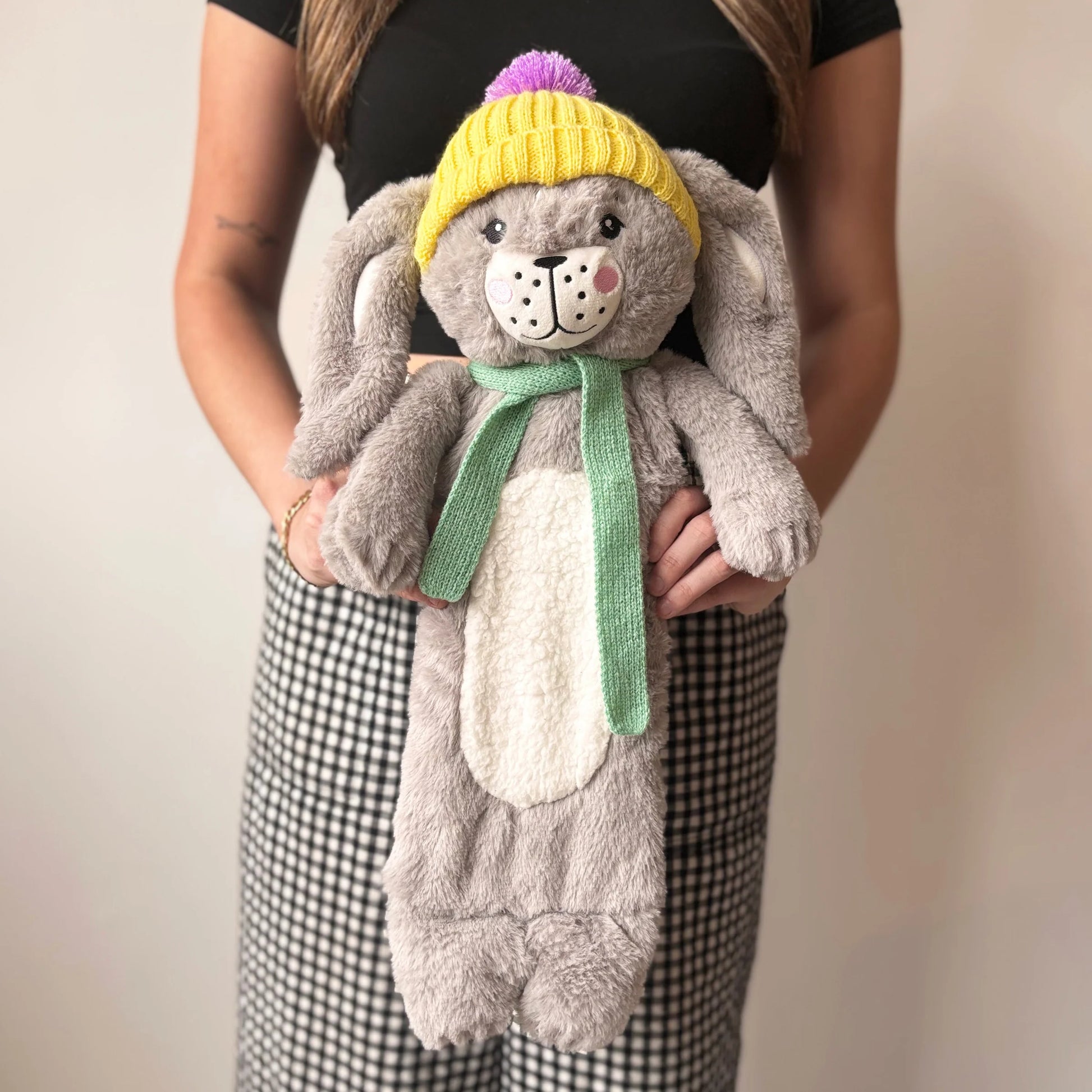 Rabbit Hot Water Bottle with yellow hat and green scarf held in hands.