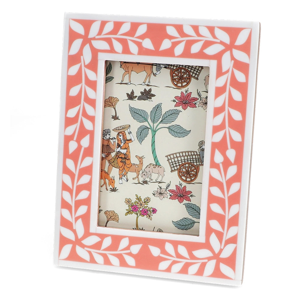 Front angle of pink resin picture frame with white leaf border and decorative insert.