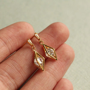 Gold vermeil rhombus crystal earrings resting on fingertips for size reference.