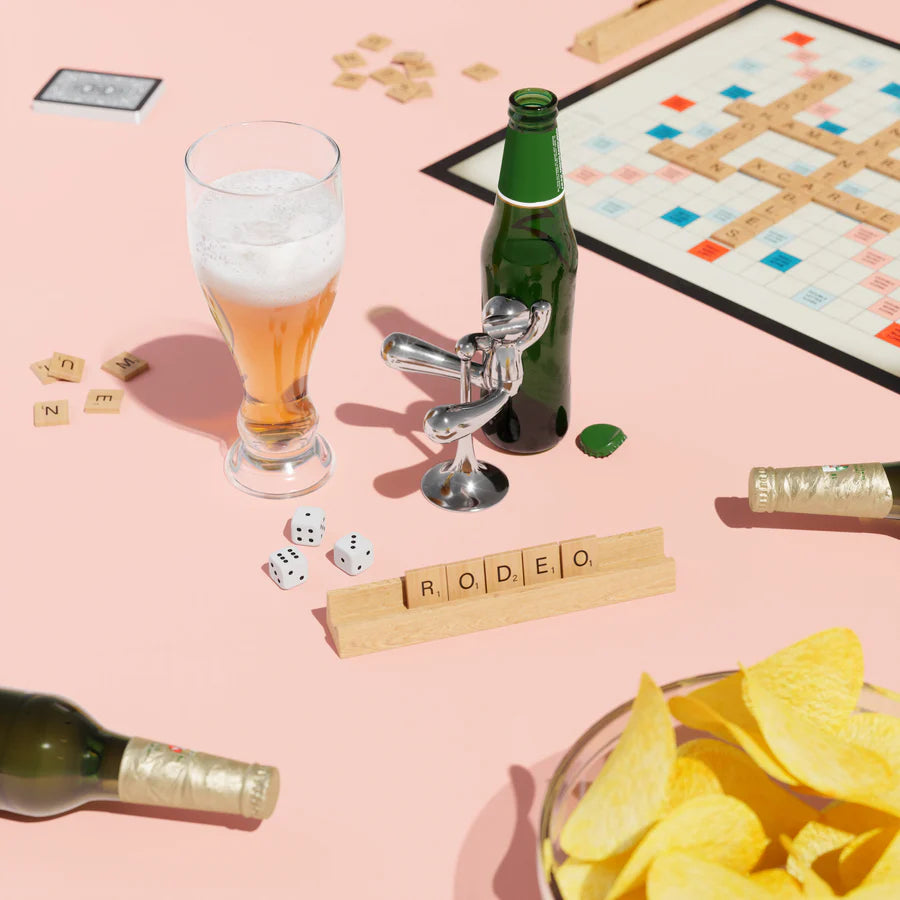 Umbra Rodeo Buddy chrome on pink background with board game and snacks