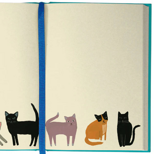Open spread of the Pretty Paws Journal showing cream-coloured pages with a row of illustrated cats along the bottom margin and a blue ribbon marker.