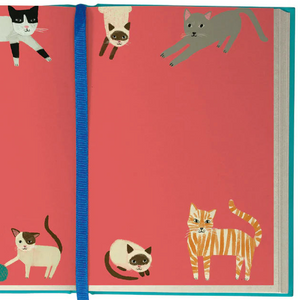Full-colour interior spread of the Pretty Paws Journal with a bold red background and playful cat illustrations scattered across both pages.