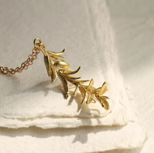 Close-up of Rosemary Botanical Leaf Necklace in gold brass with intricate leaf details on a soft background.