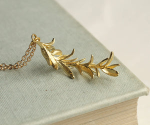 Botanical rosemary pendant resting on a book, highlighting its detailed leaf pattern and natural-inspired charm.