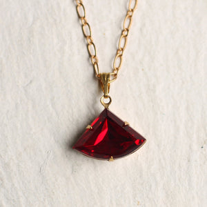 Top-down view of the Ruby Deco Necklace, highlighting the deep red hue and gold foiled backing.