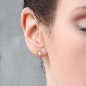 Close-up of sterling silver Sakura stud earring worn on ear – small floral earring with gold detail for everyday wear.
