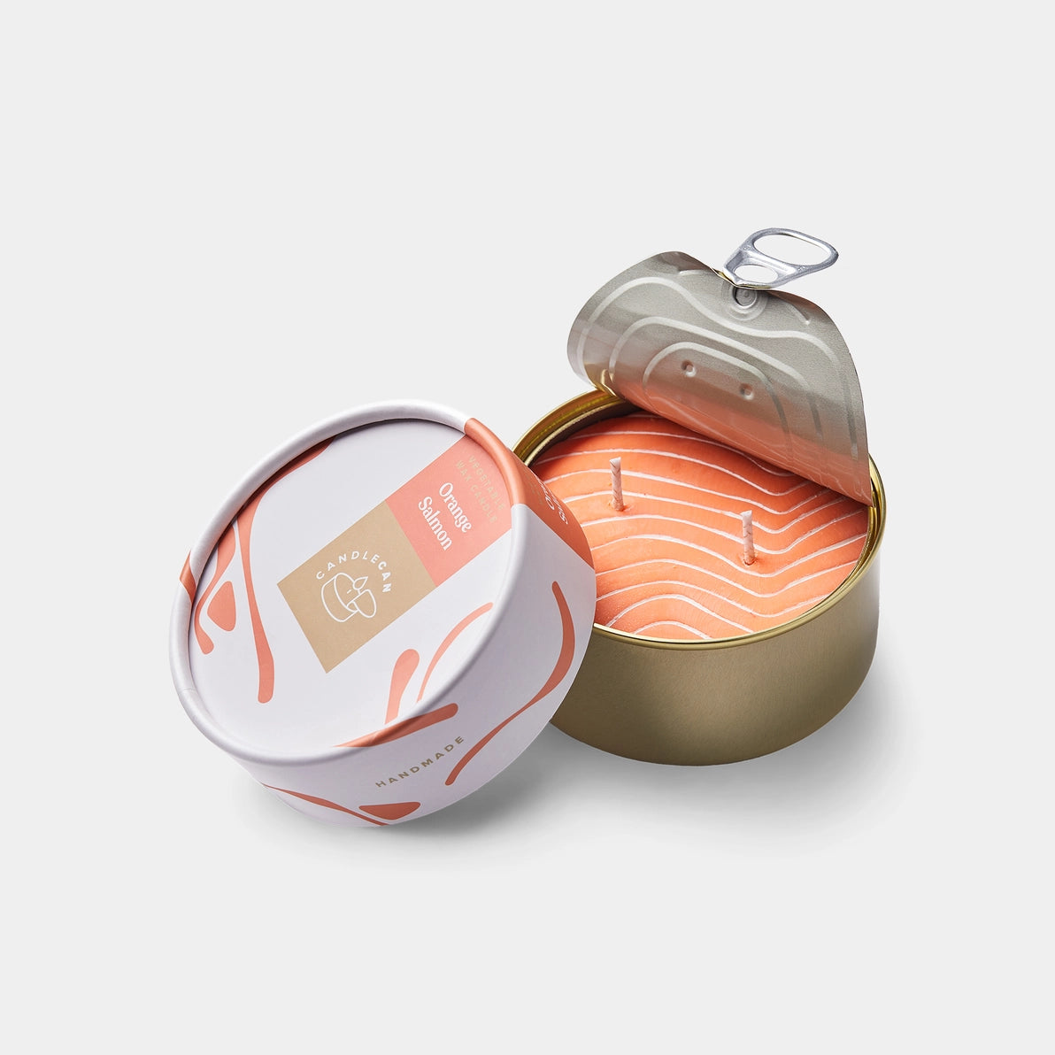 Opened Orange Salmon tin candle with pull-tab lid revealing orange wax shaped like a salmon fillet, packaged in a round designer box.