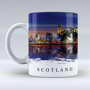 Ceramic mug with illustrated night-time Scotland skyline, featuring city landmarks and reflections on water.