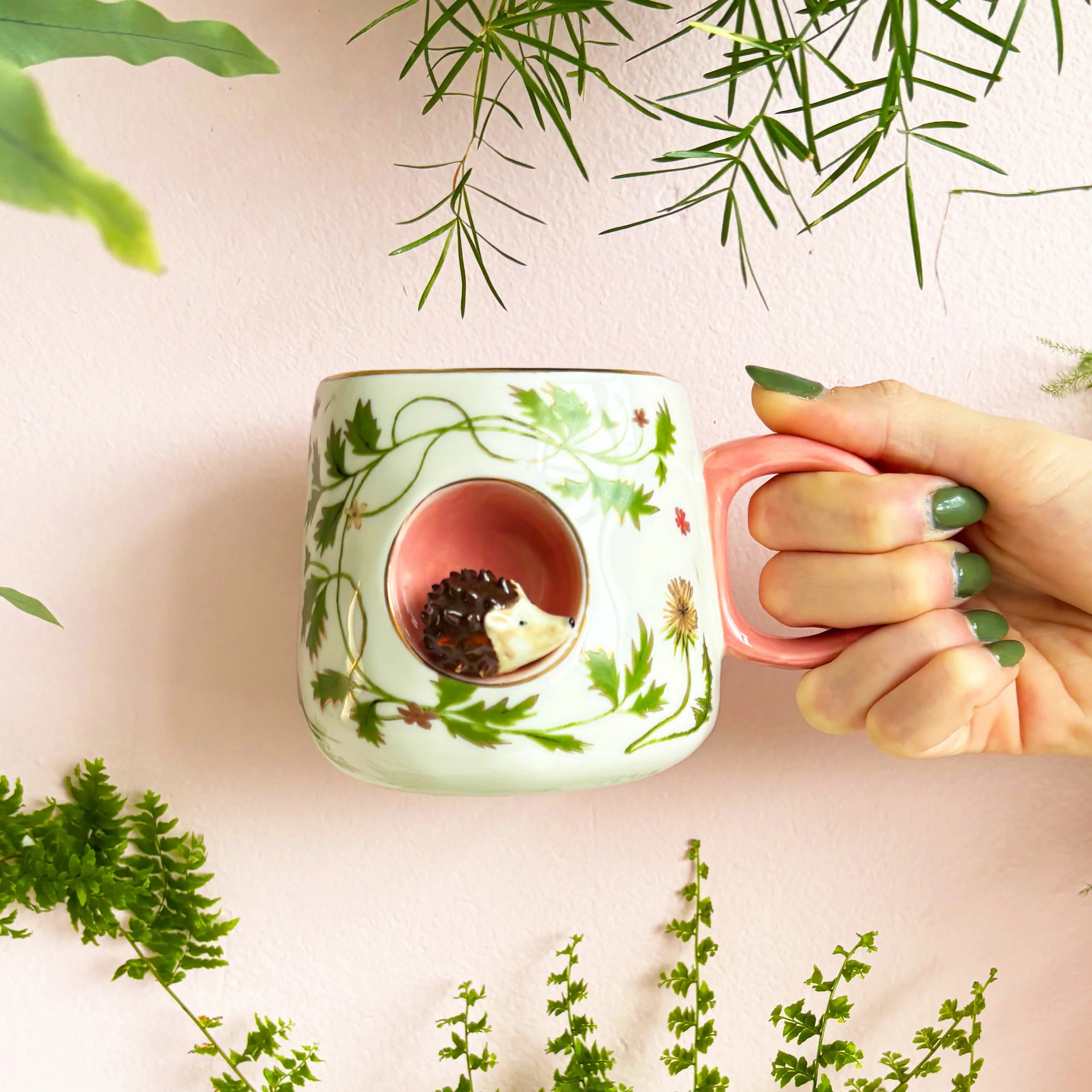 Hand holding Secret Garden Hedgehog Cup showing pink interior and 3D hedgehog detail.