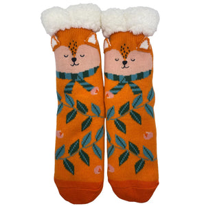 Flat lay of Secret Garden Fox Slipper Socks showing full design with sleeping fox faces, green leaves, and pink petals on vibrant orange knit.