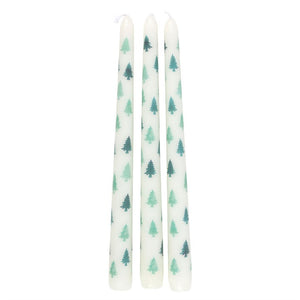 Three white taper candles with repeating green fir tree pattern standing upright.