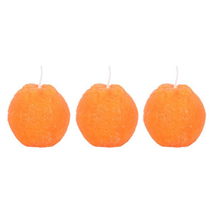 Studio shot of three vibrant orange candles shaped like oranges.
