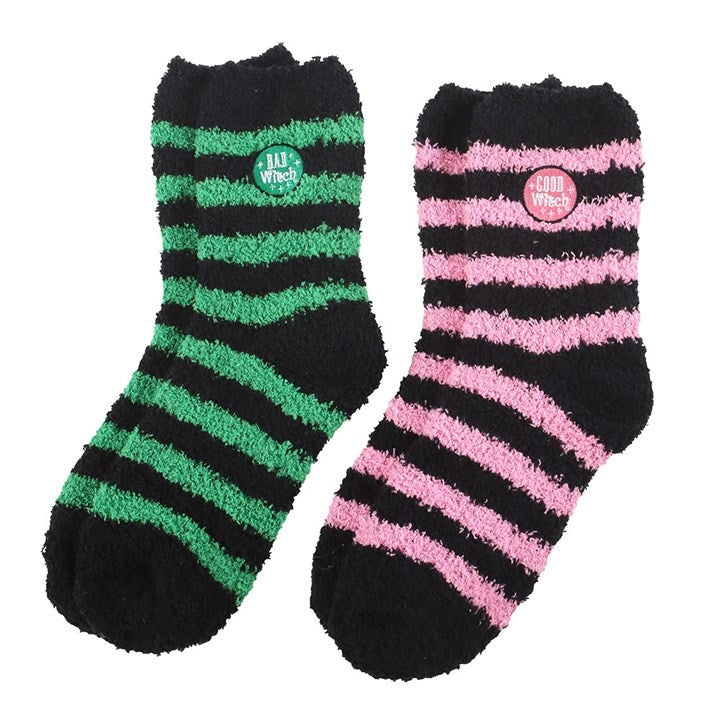 Green and pink striped witch-themed fluffy socks laid flat – Good Witch and Bad Witch design.