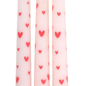 Close-up of pink taper candles with red love heart pattern, showing detail and design of Valentine’s Day candles.