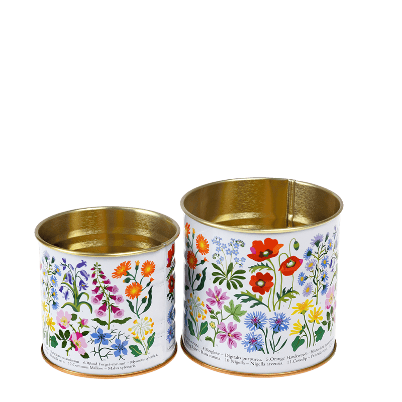 Close-up of two floral storage tins with gold interior and vintage botanical prints.