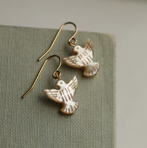 Close-up of the mother-of-pearl dove earrings reflecting light.