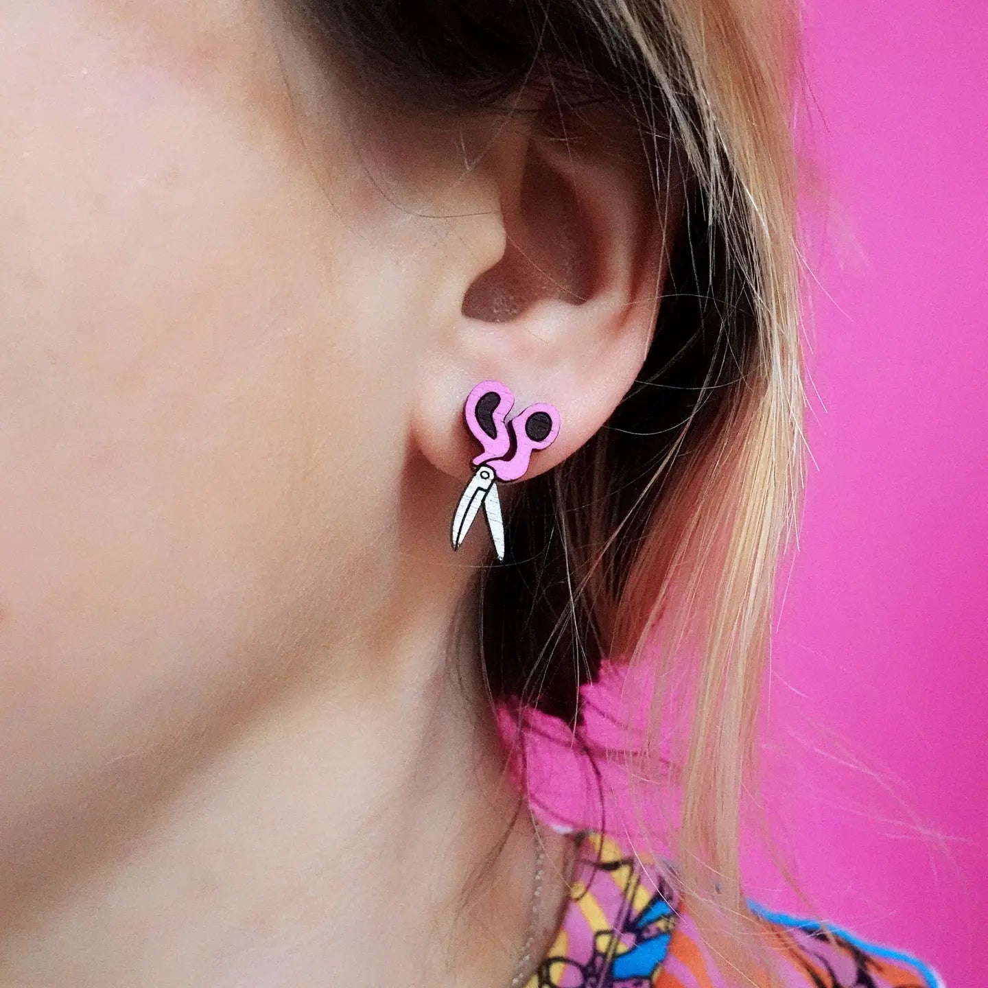 Close-up of pink scissors earring worn in ear – laser-cut wood accessory.