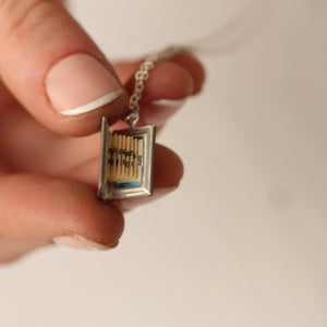 A person gently holding the open book locket, showing the hidden message or blank insert.