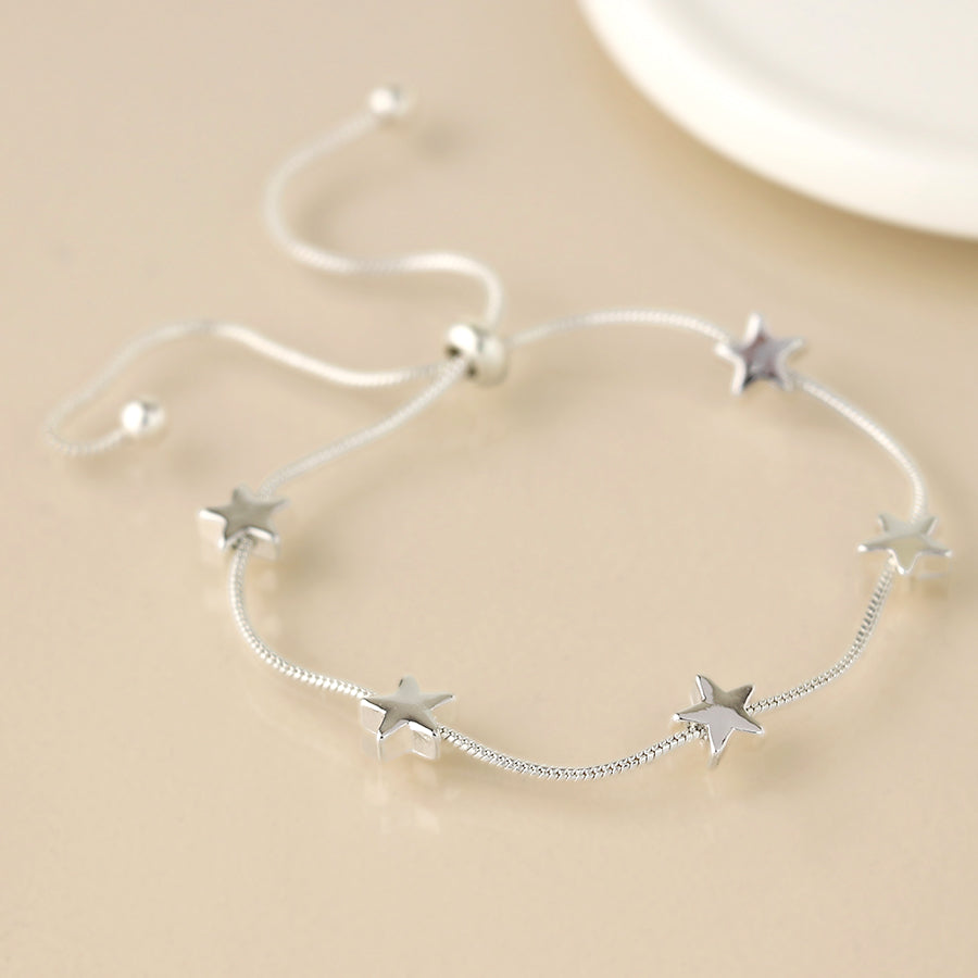 Adjustable silver star charm bracelet with delicate snake chain displayed on a neutral background.