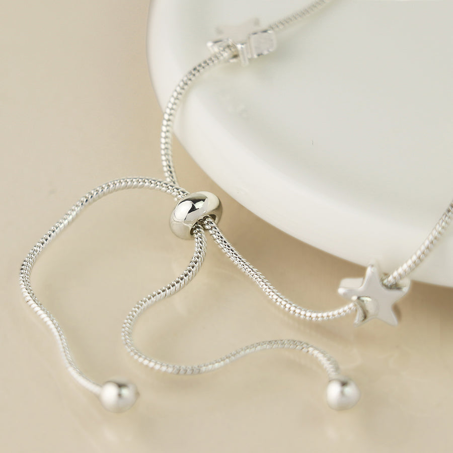 Close-up of sliding fastener on silver snake chain bracelet with star beads.
