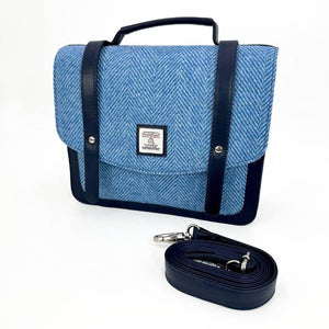 Sky blue Harris Tweed messenger bag displayed with detachable adjustable strap coiled in front.