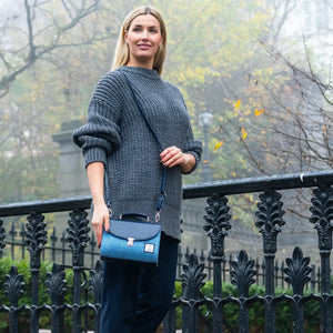 Model wearing grey jumper with Sky Blue Harris Tweed Mini Day Bag worn crossbody in city park.