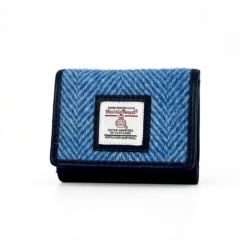 Angled view of sky blue Harris Tweed trifold purse showing herringbone pattern and front flap.
