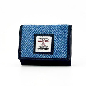 Angled view of sky blue Harris Tweed trifold purse showing herringbone pattern and front flap.