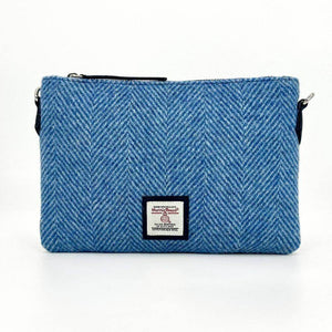 Front view of sky blue Harris Tweed clutch bag with herringbone pattern and woven Harris Tweed label.