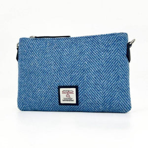 Angled front image of Harris Tweed sky blue zip bag showing herringbone weave and detachable strap attachments.