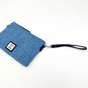 Harris Tweed sky blue clutch bag with navy faux leather wrist strap and visible metal zip.