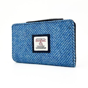Angled view of Sky Blue Harris Tweed Zip Purse showing front Harris Tweed logo and curved top edge.