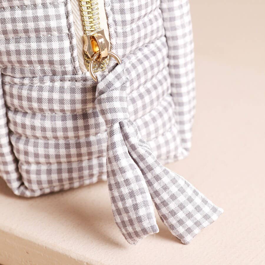 Close-up of gold zip with gingham fabric pull detail on small linen wash bag.