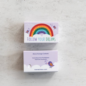 Front and back view of the Follow Your Dreams matchbox with rainbow artwork and product details.