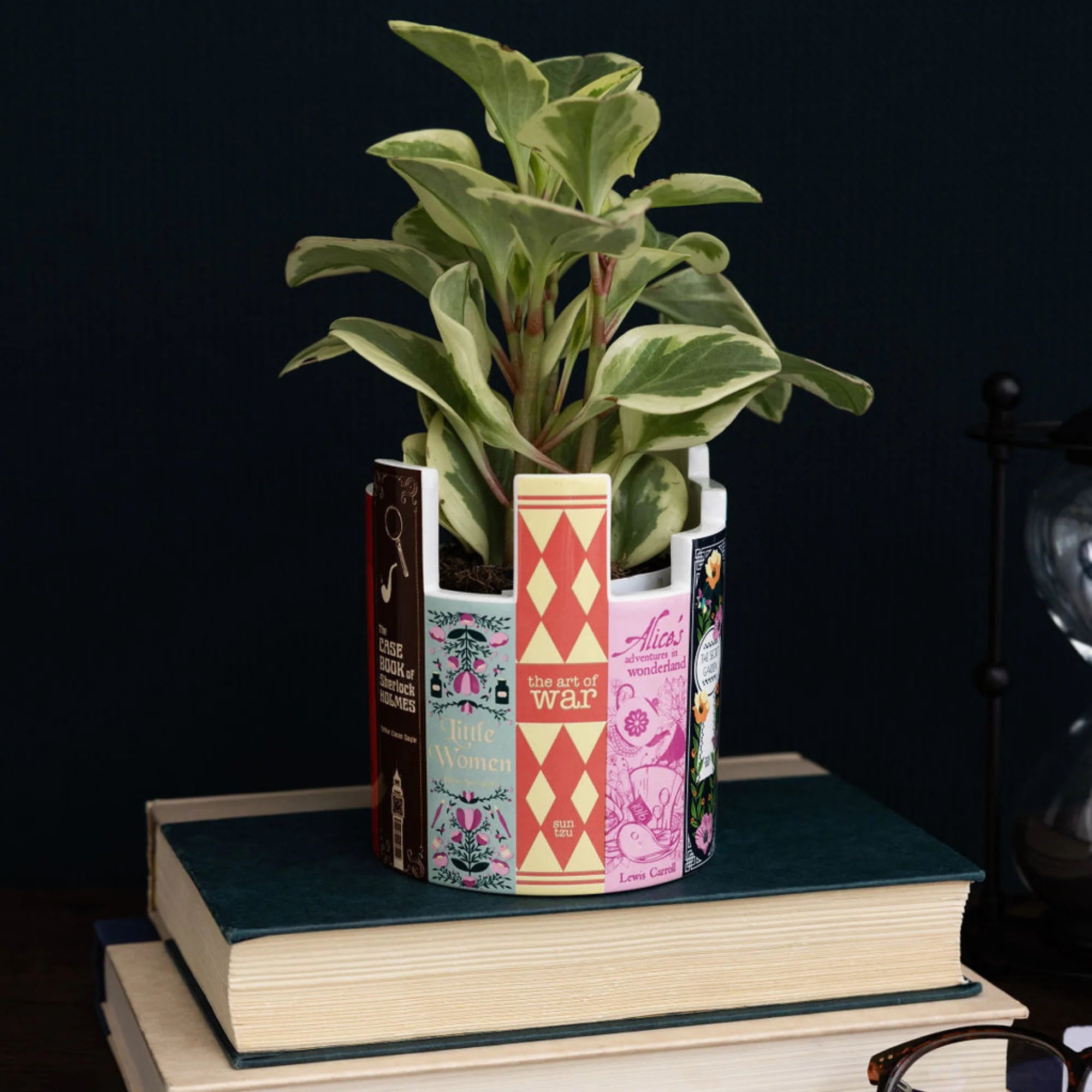 Classic book stack ceramic desk pot styled as a plant holder, placed on stacked books with a leafy green plant inside.
