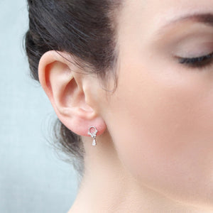 Sterling silver droplet hoop stud earring worn in pierced ear, showcasing size, fit, and sparkle of the cubic zirconia crystal design on model’s earlobe.