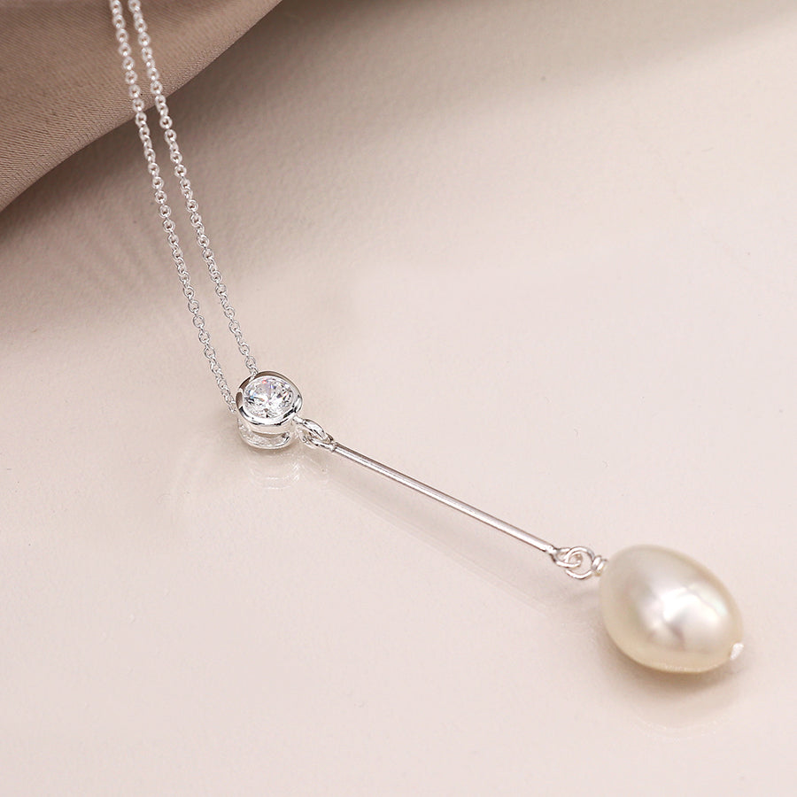 Close-up of CZ crystal and ivory pearl drop on sterling silver chain.