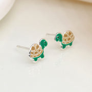 Sterling silver turtle stud earrings with green enamel shell and cream detailing, shown side-by-side on a neutral background.